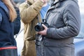 The person standing in crowd holds in hand the camera