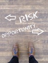 Person standing on the floor that has the risk opportunity and arrows text printed on it Royalty Free Stock Photo