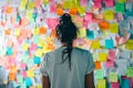 person standing in front of a wall covered in sticky notes, organizing ideas