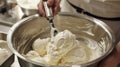 A person is standing in a kitchen, using a hand mixer to mix a bowl of creamy, cold ice cream Royalty Free Stock Photo