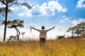 A person standing in large field enjoying the nature under beautiful blue sky