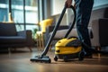 a person standing in a modern living room with hardwood floors, using a yellow cordless vacuum