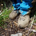 A person standing in Muddy hiking boots and gaiters