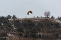 Person standing at paraglide launch site with paraglider up in the wind on hill in winter with snow ready to start Royalty Free Stock Photo