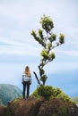 Person standing on the precipice of a hill, admiring the majestic view of mountain in background