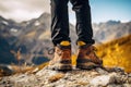 A person standing triumphantly atop a rugged mountain peak, overlooking a breathtaking panorama, focus on shoes of cropping,