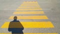 A person stands at the beginning of a pedestrian crossing, where it is written stop and waits for the passage time, on the yellow