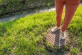 A person stands on a rusty manhole cover near gutter with water Royalty Free Stock Photo