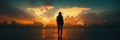 Person stands in silhouette before a glowing world map at sunset in an open space with minimal light Royalty Free Stock Photo