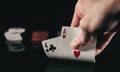 Person subtly raising poker cards on black background