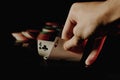 Person subtly raising poker cards on black background