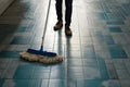 Person sweeps tile floor with dust mop, maintaining cleanliness