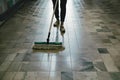 Person sweeps tile floor with dust mop, maintaining cleanliness