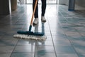 Person sweeps tile floor with dust mop, maintaining cleanliness