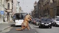 Person in T Rex costume prankster walking at city street crosswalk