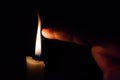 A person takes his finger very close to candle flame