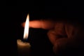A person takes his finger very close to candle flame