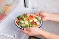 A person is taking a plate of frozen vegetables out of the freezer of the fridge. Concept of frozen food Royalty Free Stock Photo