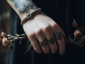 A person with tattoos on their hands holding a flower. Generative AI image. Royalty Free Stock Photo