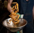 Person tossing freshly cooked fries with spices on a mixing bowl