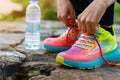 person tying laces on colorful sneakers with water bottle beside