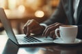 A person typing on a laptop with a coffee cup beside them in a cozy setting Royalty Free Stock Photo