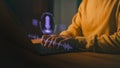 Person typing on laptop computer with glowing voice assistant icon, representing AI voice recognition, speech-to-text Royalty Free Stock Photo