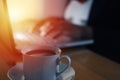 Person typing on laptop in dark condition, writer work on computer, focus on coffee with blur defocused background