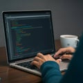 Person typing on a laptop displaying colorful lines of code in a text editor, likely JavaScript or JSON. Royalty Free Stock Photo