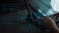 Person typing on laptop with glowing code overlay, representing programming, coding, technology, and digital innovation Royalty Free Stock Photo