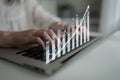 Person typing on laptop while interactive graph appears, showcasing financial growth and data analysis in modern Royalty Free Stock Photo