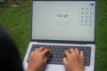 Person typing on laptop keyboard using Google search engine