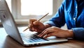 AI-generated Person Typing On Laptop With Pencil In Hand For Work, Study, And Online Tasks Royalty Free Stock Photo