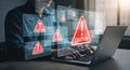 Person typing on laptop with caution signs and code overlays indicating cybersecurity threat detected Royalty Free Stock Photo