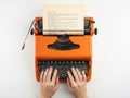 Person typing on orange typewriter isolated on white background Royalty Free Stock Photo