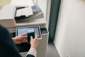 A person uses a smartphone to operate a modern printer in a corporate office setting