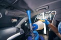 Person using auto detailing dry cleaning gun on car ceiling