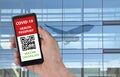 Person using digital health passport app in mobile phone with an unidentifiable QR code for travel during covid-19 pandemic.