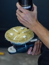 a person using a drill on a cake with cream frosting