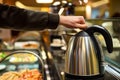 person using electric kettle at a selfservice hotel breakfast area