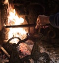 Person using a fire iron to stoke the flames