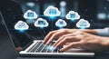 A person using a laptop with cloud computing icons floating above the keyboard and screen Royalty Free Stock Photo