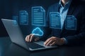 Person using laptop with glowing cloud and document icons representing cloud storage and data management Royalty Free Stock Photo