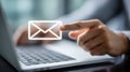 Person using laptop while pointing toward digital envelope icon representing email communication and online messaging services in Royalty Free Stock Photo