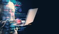 Person using a laptop with programming code overlay on a dark background Royalty Free Stock Photo
