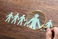 Person Using Magnifying Glass On Cut-out Figures Royalty Free Stock Photo