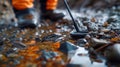 A person is using a metal detector in a sunlit shallow stream, scanning the rocky bed Royalty Free Stock Photo