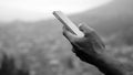 Person using phone. Hands of a business man holding cigarette while checking cellphone in black and white background Royalty Free Stock Photo