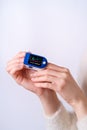 Person using pulse oximeter device on finger, healthcare monitoring concept