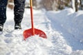 Person using a red shovel to clear a pathway covered in deep, fresh white snow Royalty Free Stock Photo